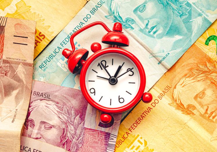  A small red alarm clock on banknotes of the Brazilian Real