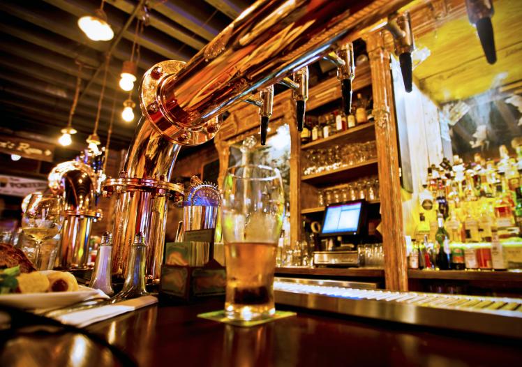 Glass of beer and beer taps in a bar