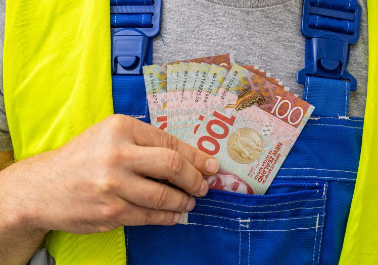 Worker counting his earnings, New Zealand money