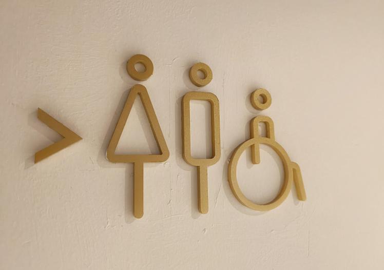 Toilet sign board hanging on wall.