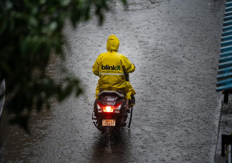 Blinkit gig driver on moped in the rain