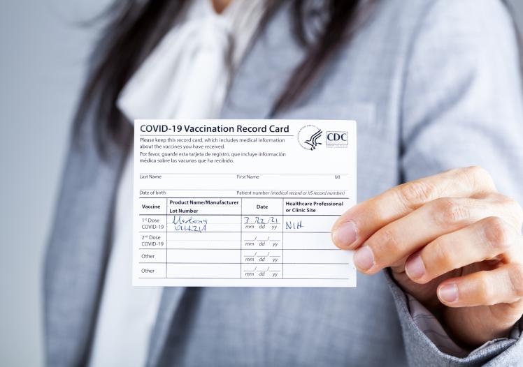 Woman showing Vaccination record card