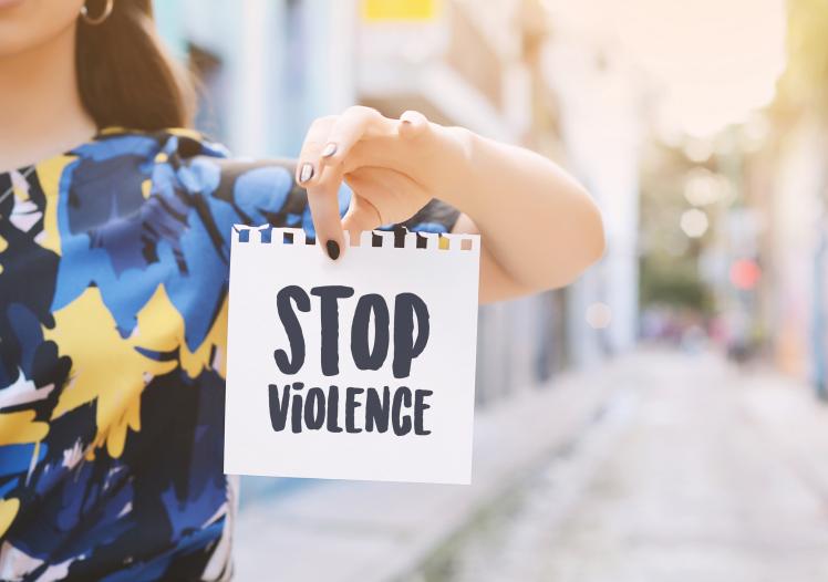 Young woman showing a notepad with the text "stop violence"