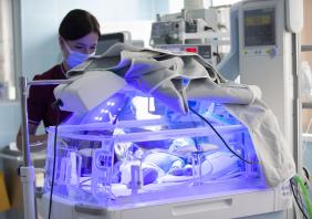 A newborn baby is treated for jaundice under ultraviolet light in an incubator.