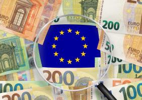 Euro notes with Europe Union flag view through magnifying glass