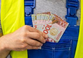 Worker counting his earnings, New Zealand money