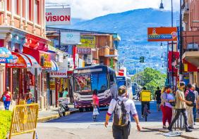 Colorful bus busses in busy traffic and cityscape with stores people and cars in San José Costa Rica