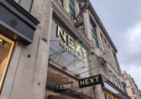 Next flagship store with Costa Coffee sign and bronze statue on Oxford Street in London