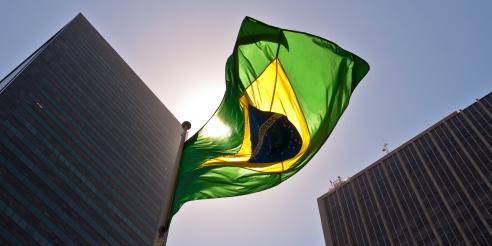 A Brazilian flag in front of skyscrapers