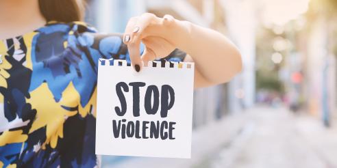 Young woman showing a notepad with the text "stop violence"