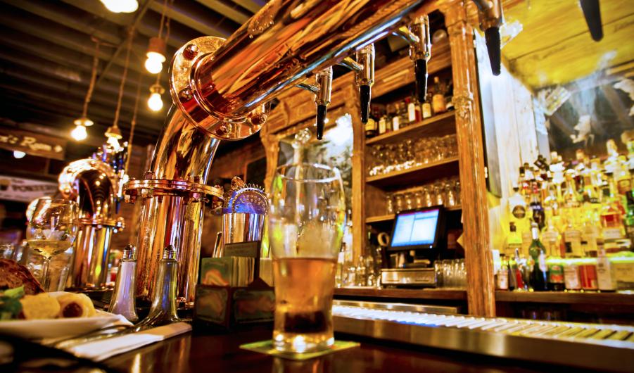 Glass of beer and beer taps in a bar