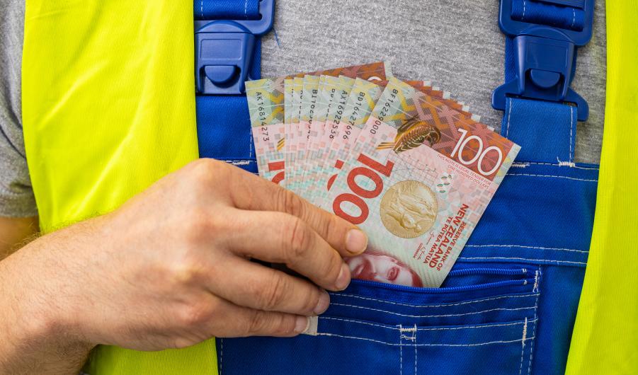 Worker counting his earnings, New Zealand money